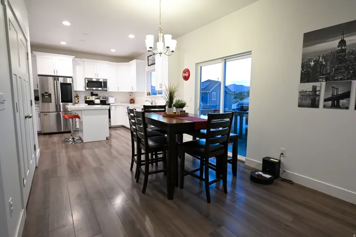 Open-concept kitchen and dining area featuring wood-finish flooring, white cabinetry, and stainless steel appliances