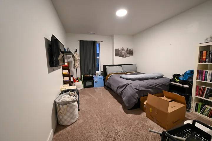 Spacious room featuring neutral carpeting, a window with dark drapery, a wall-mounted television, and recessed ceiling lighting