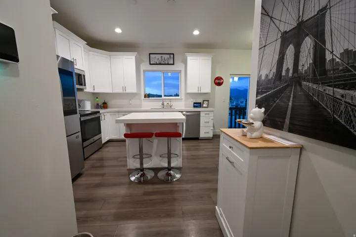 Modern kitchen featuring white cabinetry, stainless steel appliances, a center island with countertop seating, wood-finish flooring, and recessed lighting