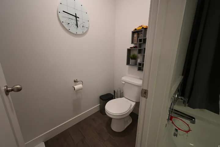 Bathroom featuring wood-finish flooring, a white toilet, and a white bathtub with chrome fixtures