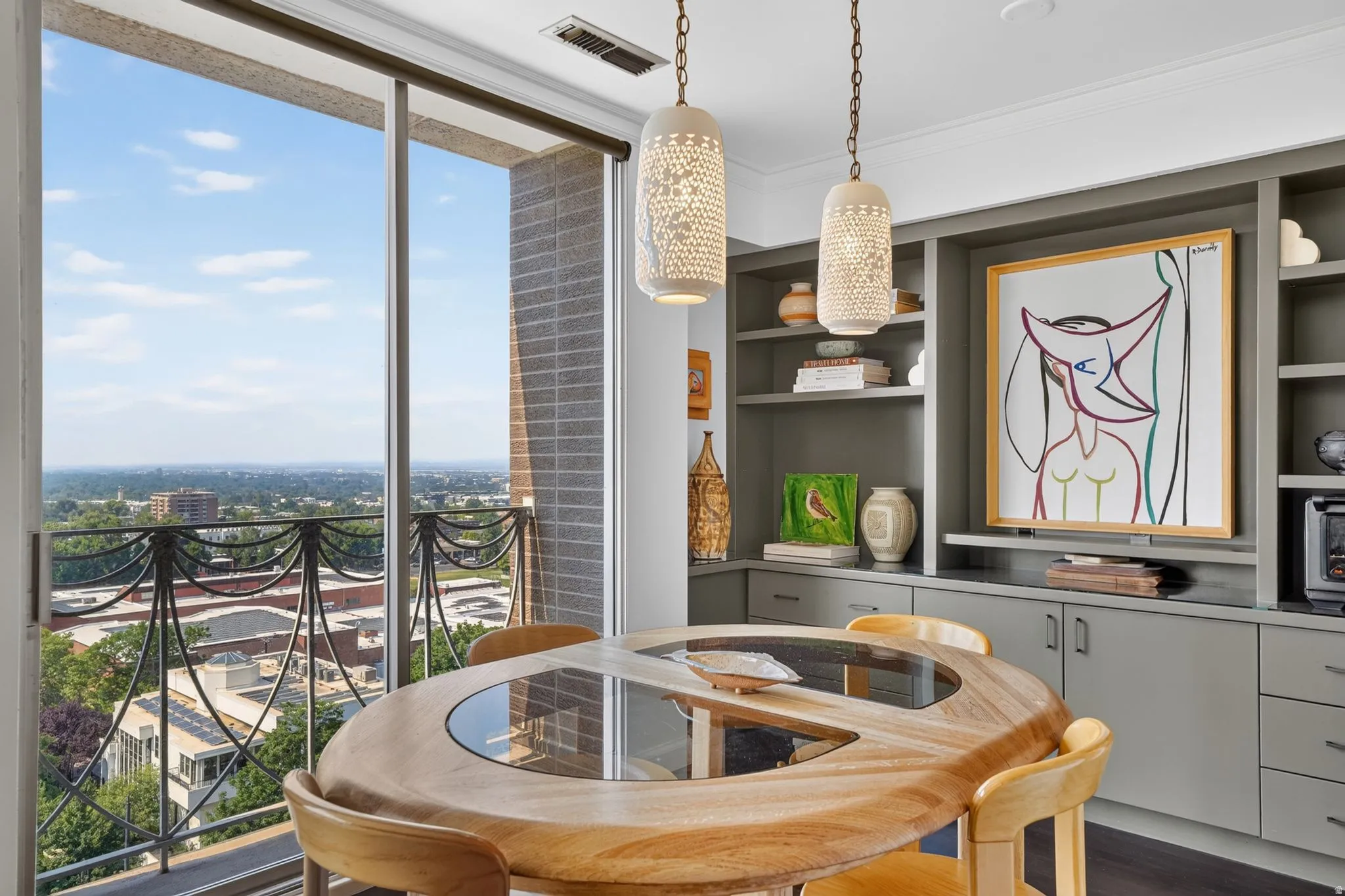 Expansive glass sliding doors open to a balcony with intricate metal railings, offering a broad cityscape