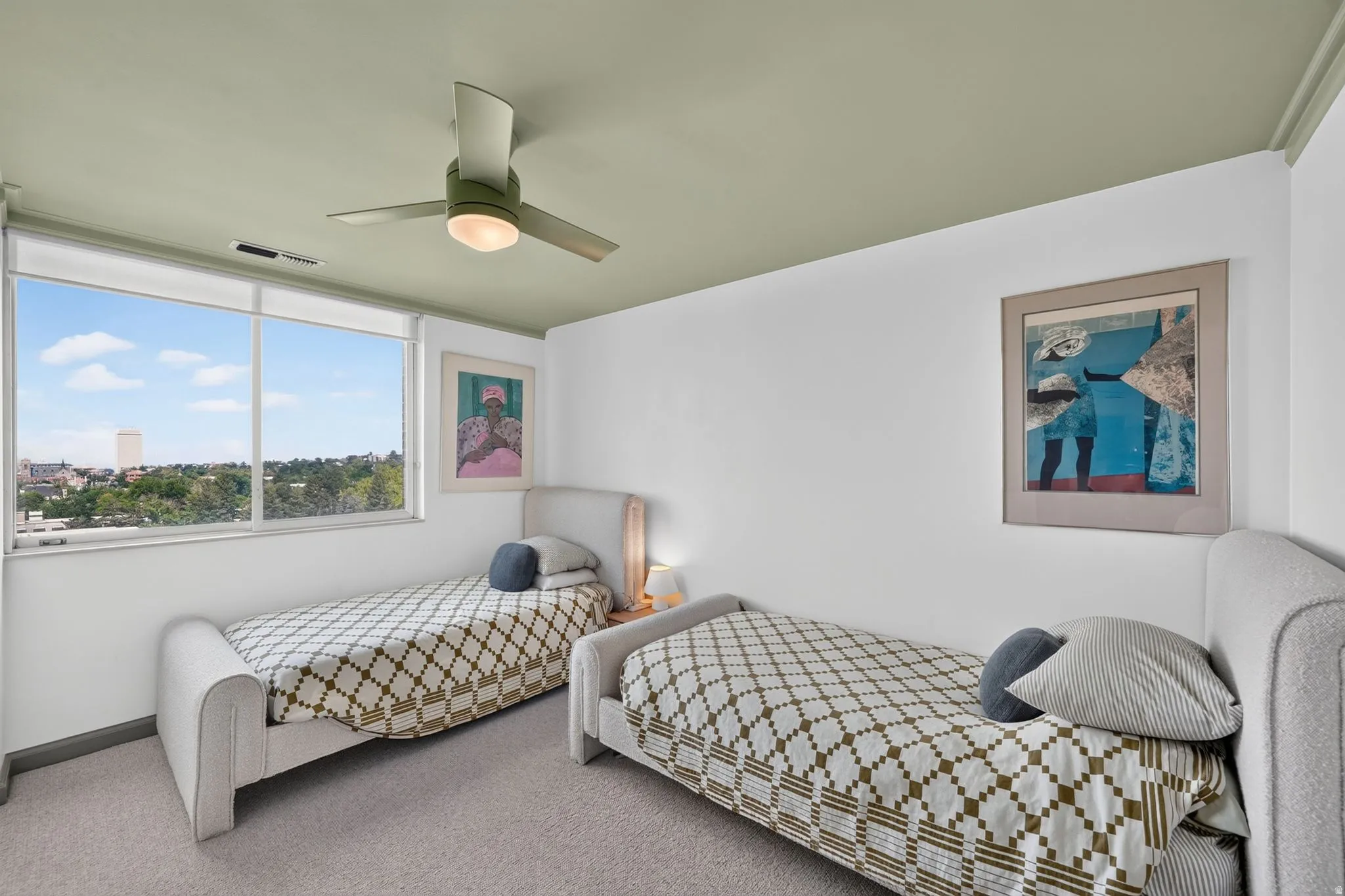 Room featuring broad windows, a ceiling fan, and light-colored carpet flooring
