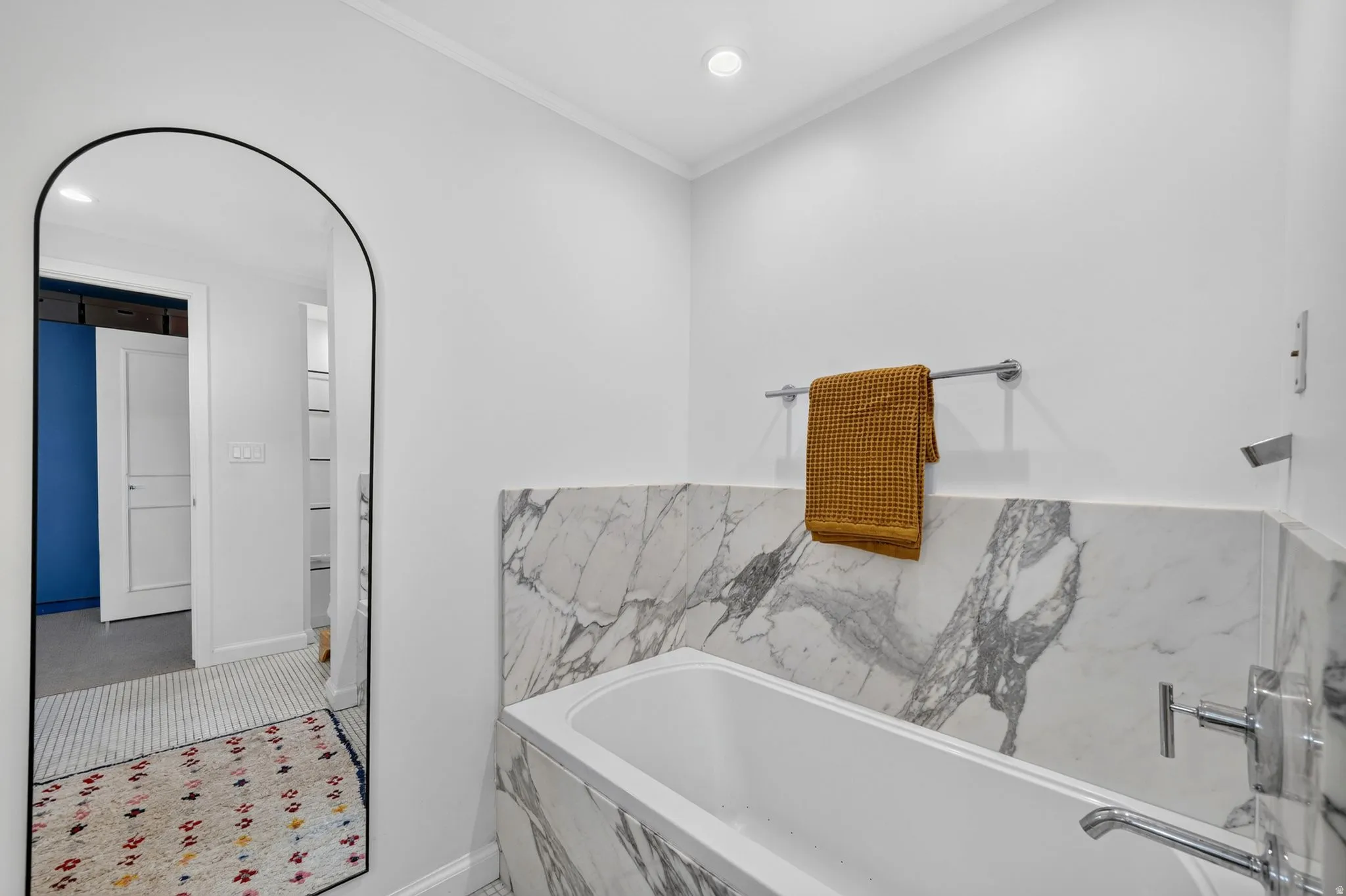 Soaking tub with marble surround, chrome fixtures, and recessed lighting