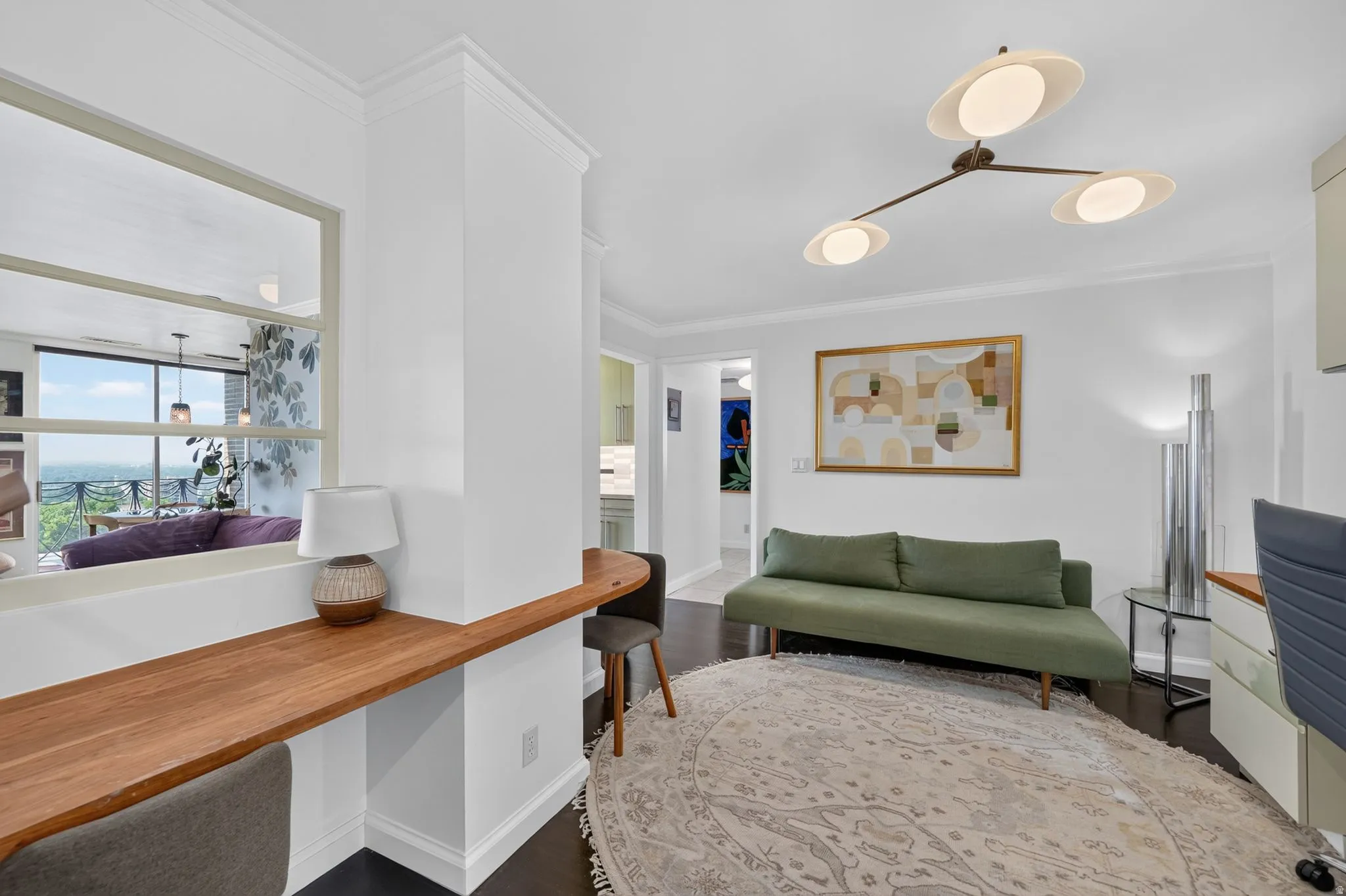 Built-in wood-finish desk with a pass-through window, dark wood-finish flooring, and a contemporary ceiling light fixture