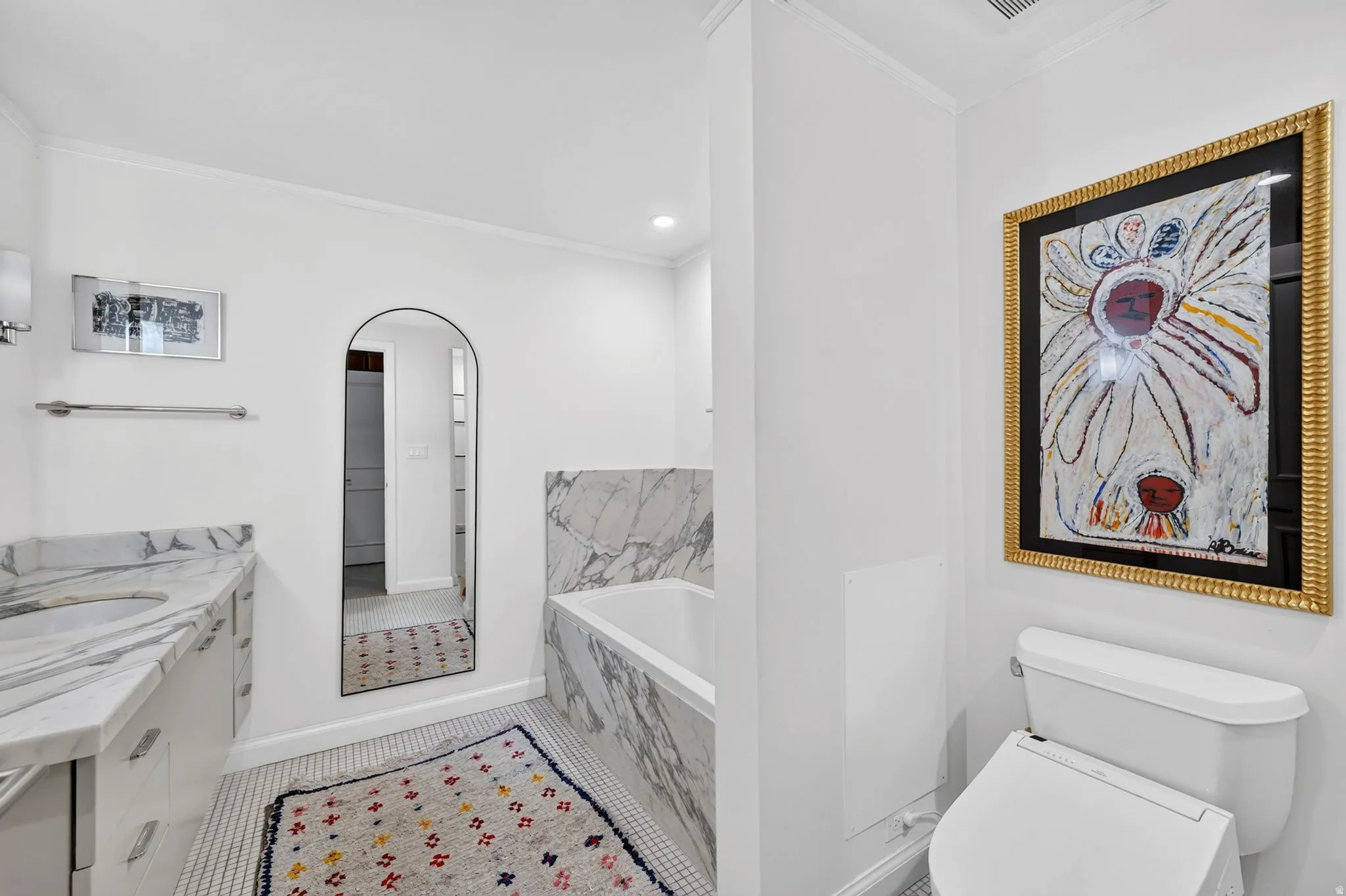 Bathroom featuring a built-in tub with a stone surround, a white vanity with a stone countertop and integrated sink, and white hex tile flooring