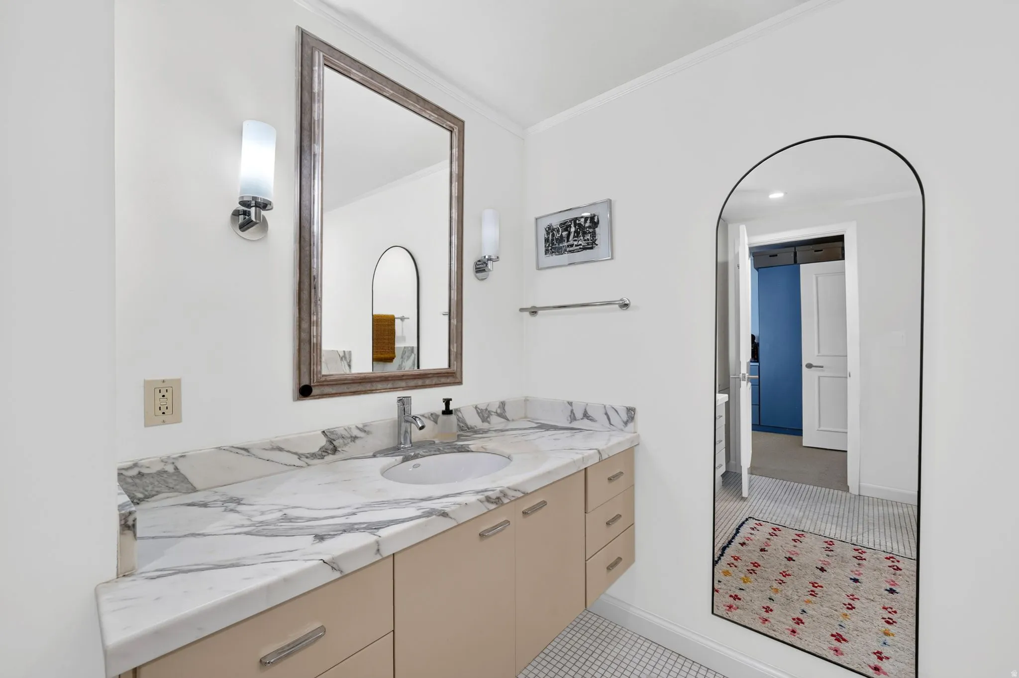 Bathroom vanity featuring a light-colored countertop with gray veining, an undermount sink, and a single-handle faucet
