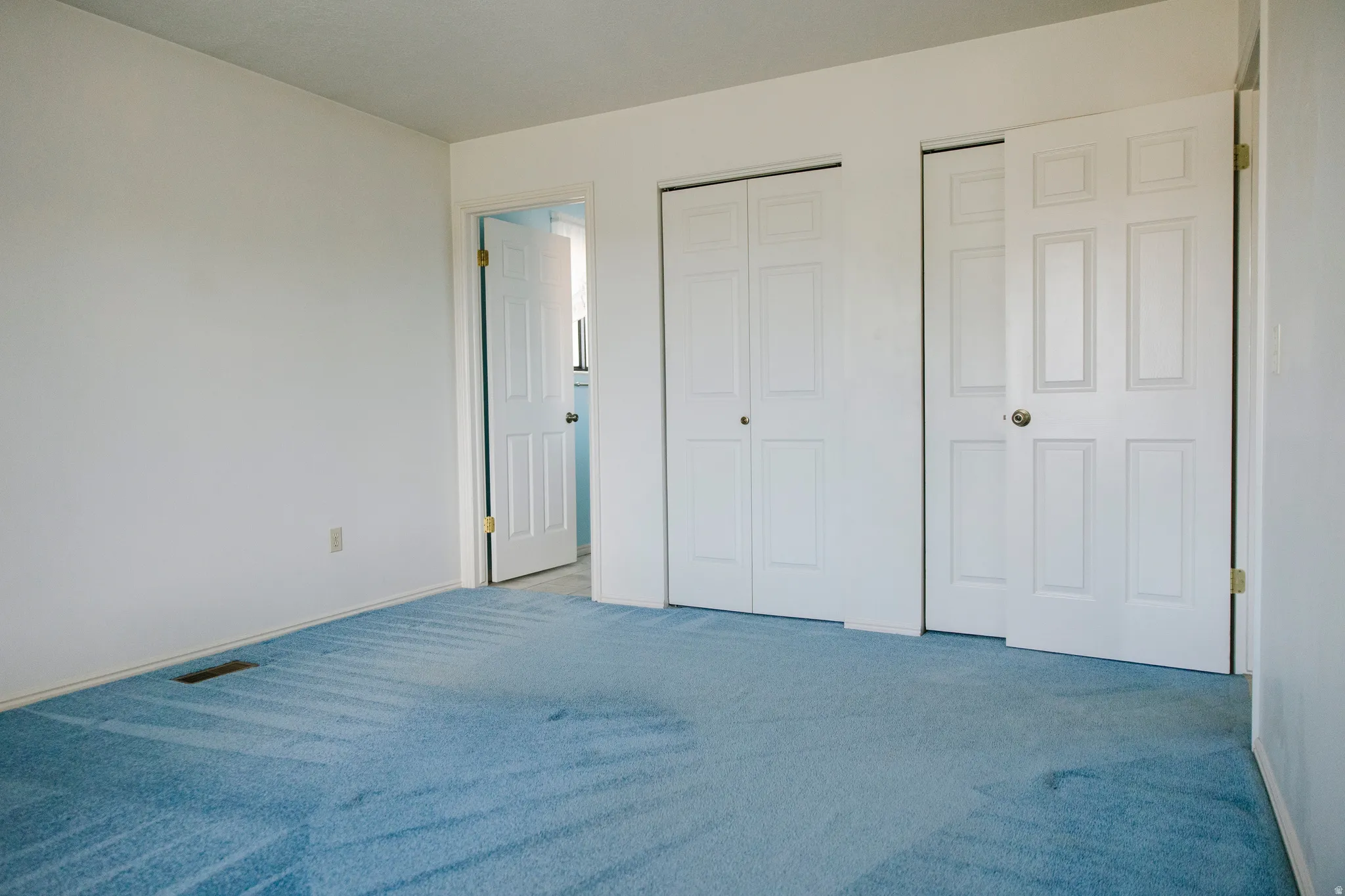 Spacious room with light blue carpeting and white walls