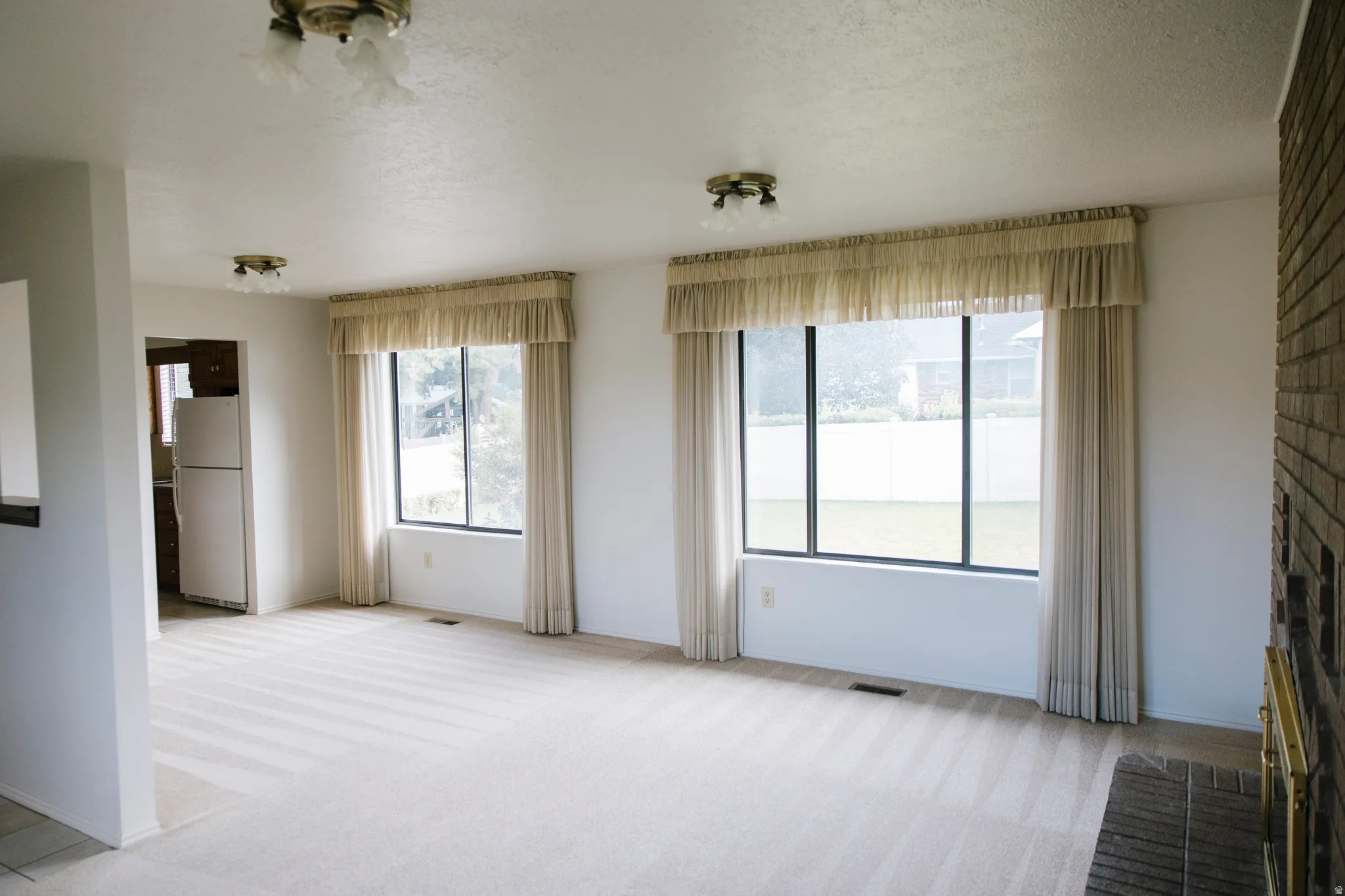 Living area with light-toned wall-to-wall carpeting and multiple large windows