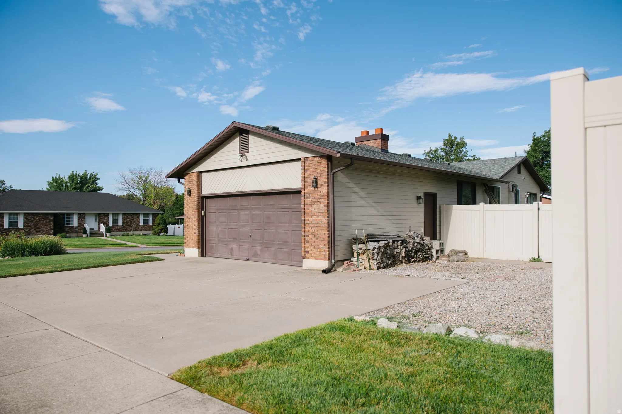 Attached two-car garage with a brown panel door, brick facade, and light siding