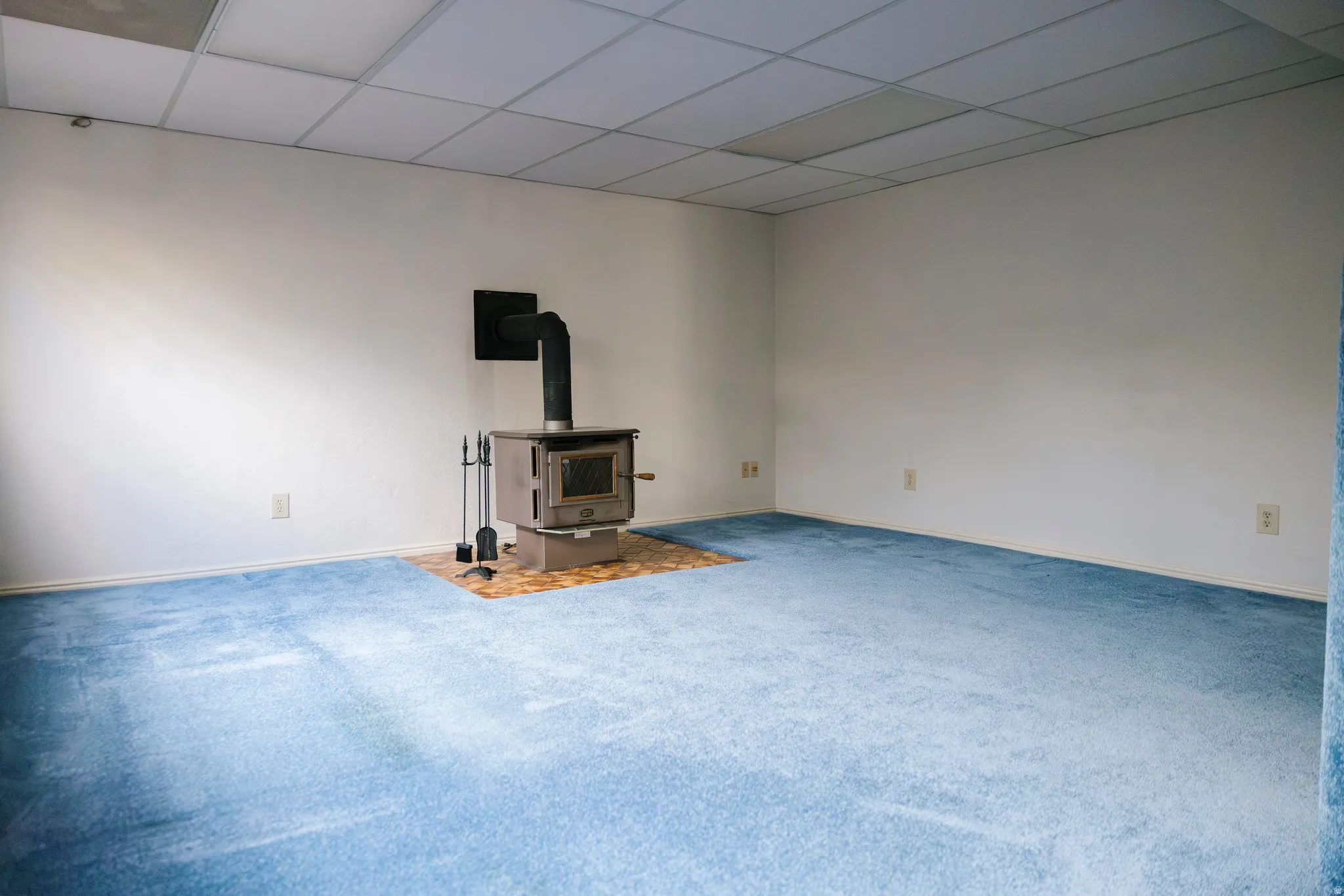 Spacious room featuring a central wood-burning stove on a tiled hearth