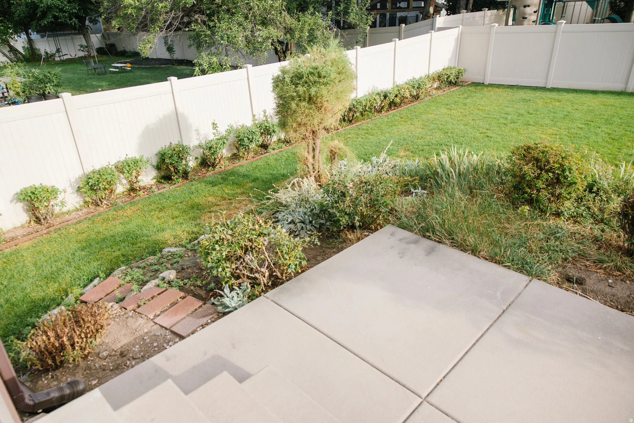 Expansive backyard featuring a lush lawn, established perimeter shrubbery, and a full privacy fence