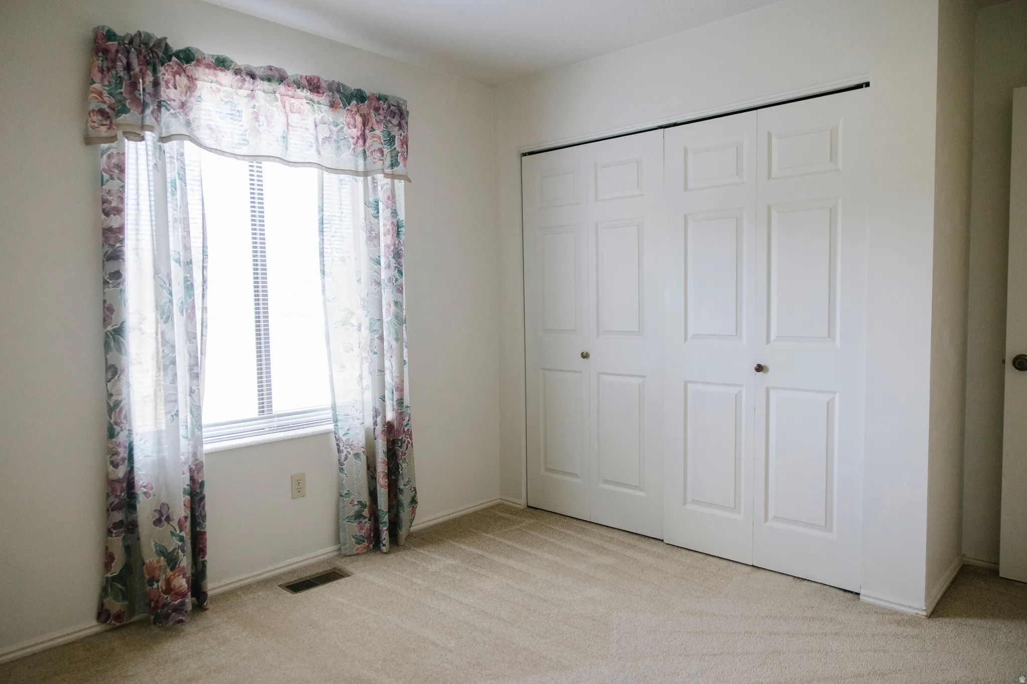 Spacious room featuring neutral carpet flooring and white walls
