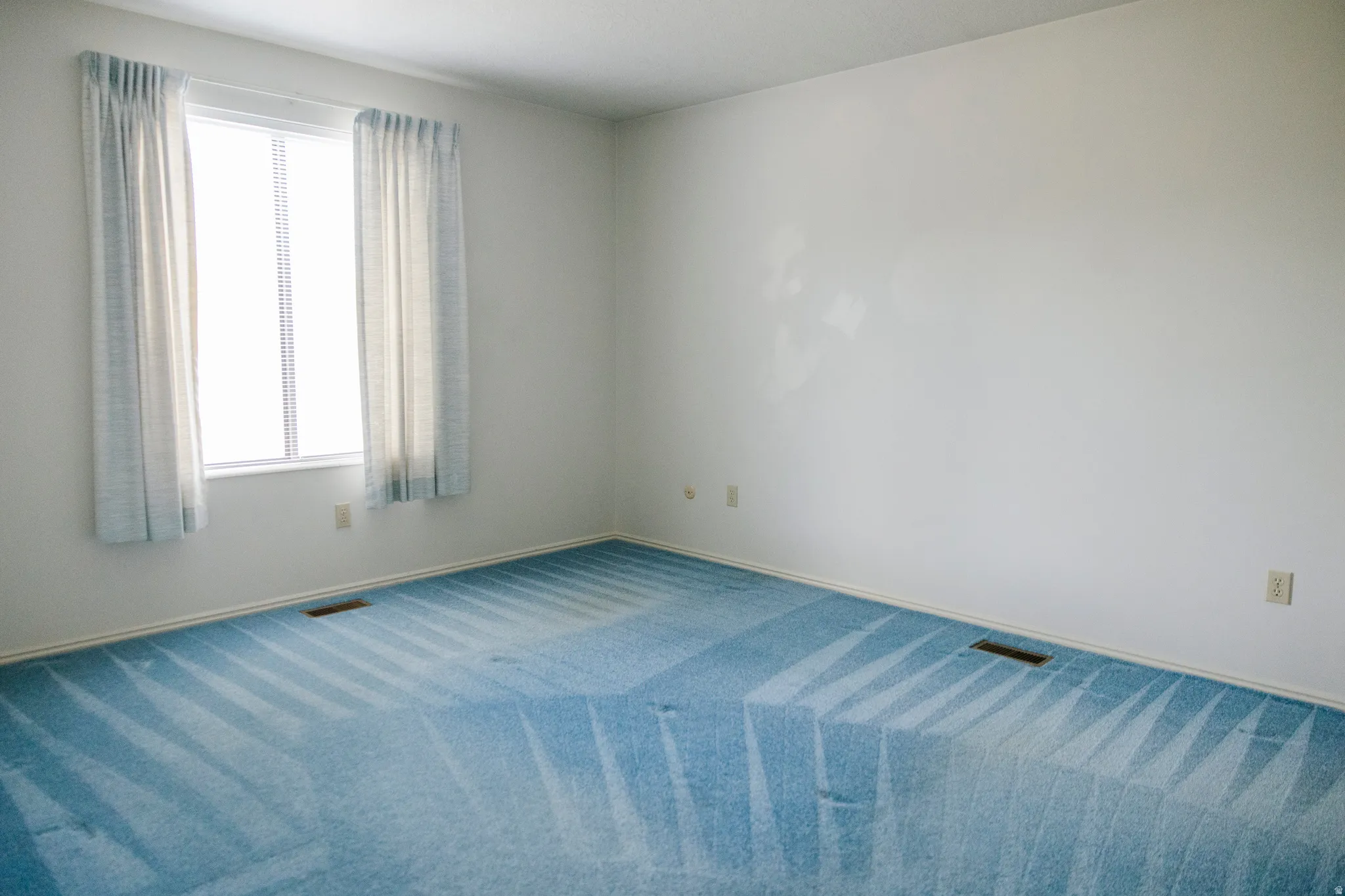Room featuring light blue patterned carpeting, white painted walls, and white baseboards