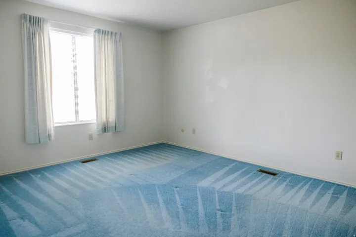 Room featuring light blue patterned carpeting, white painted walls, and white baseboards