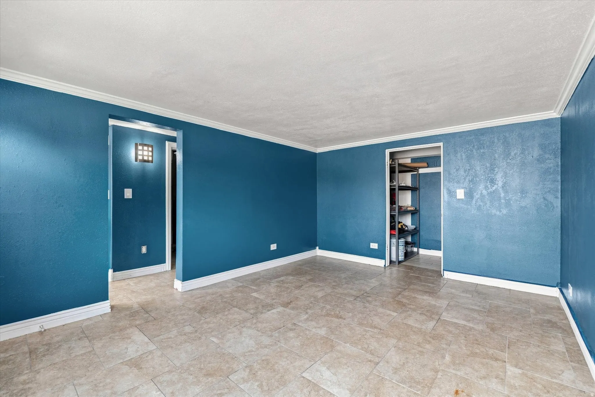 Tiled flooring throughout, crown molding, and an open doorway with built-in shelving