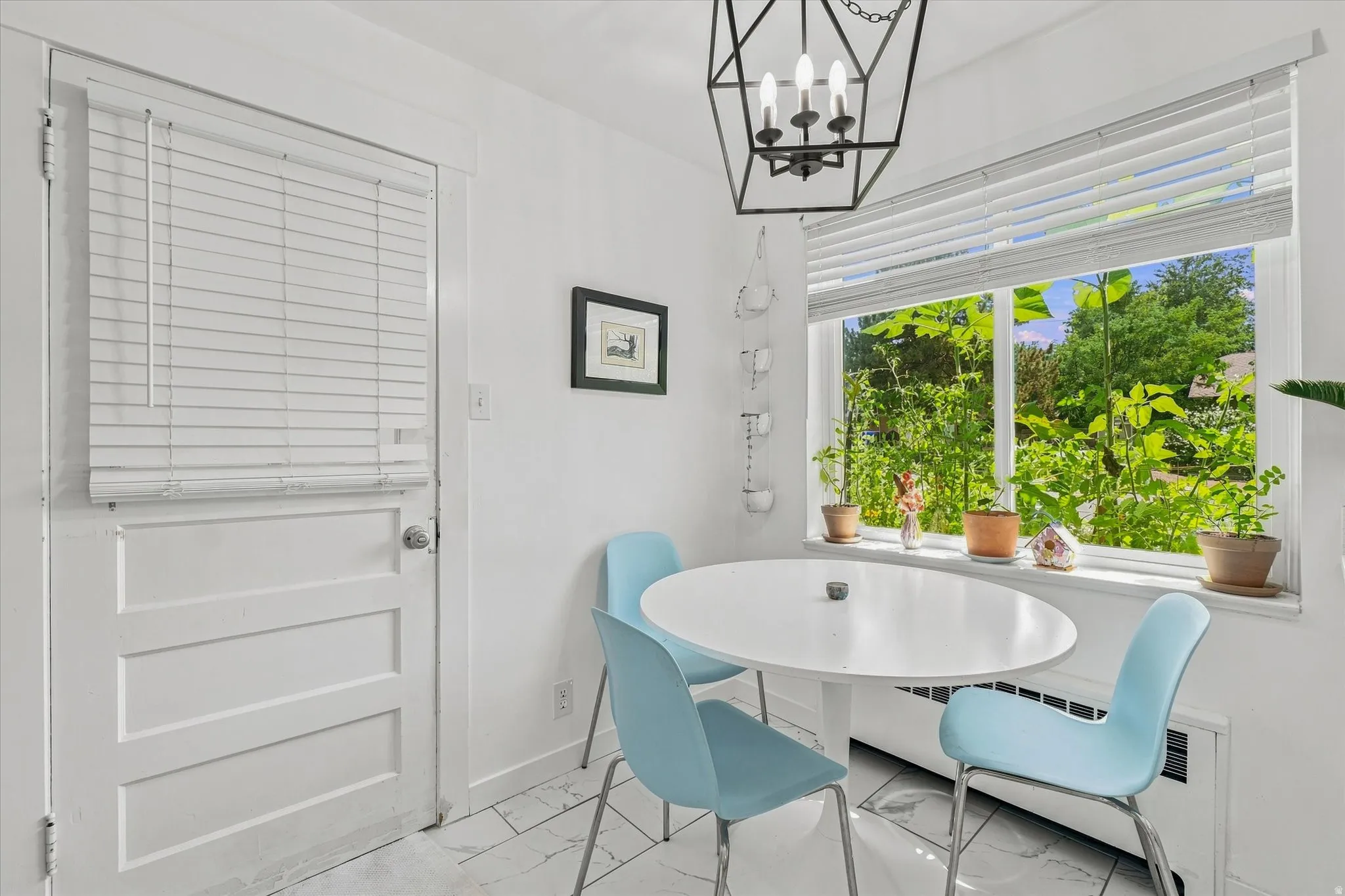 Large window with white blinds, white paneled door, black geometric chandelier, and white tile flooring