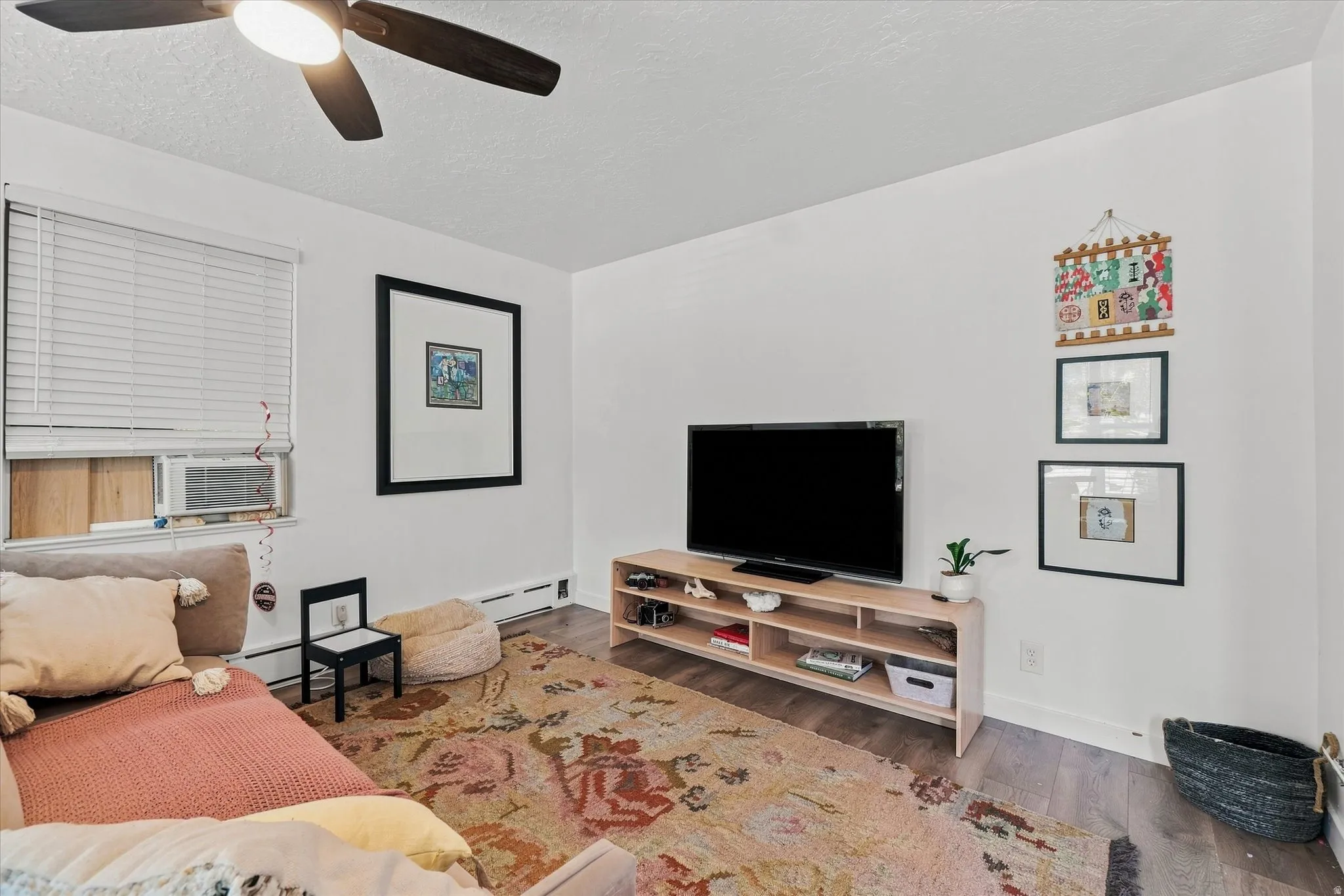 Wood-finish flooring, white walls, and a ceiling fan with integrated lighting