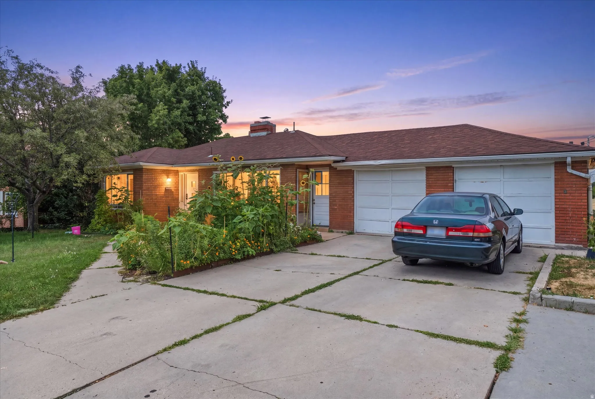 Brick exterior, pitched roof, attached two-car garage, and concrete driveway
