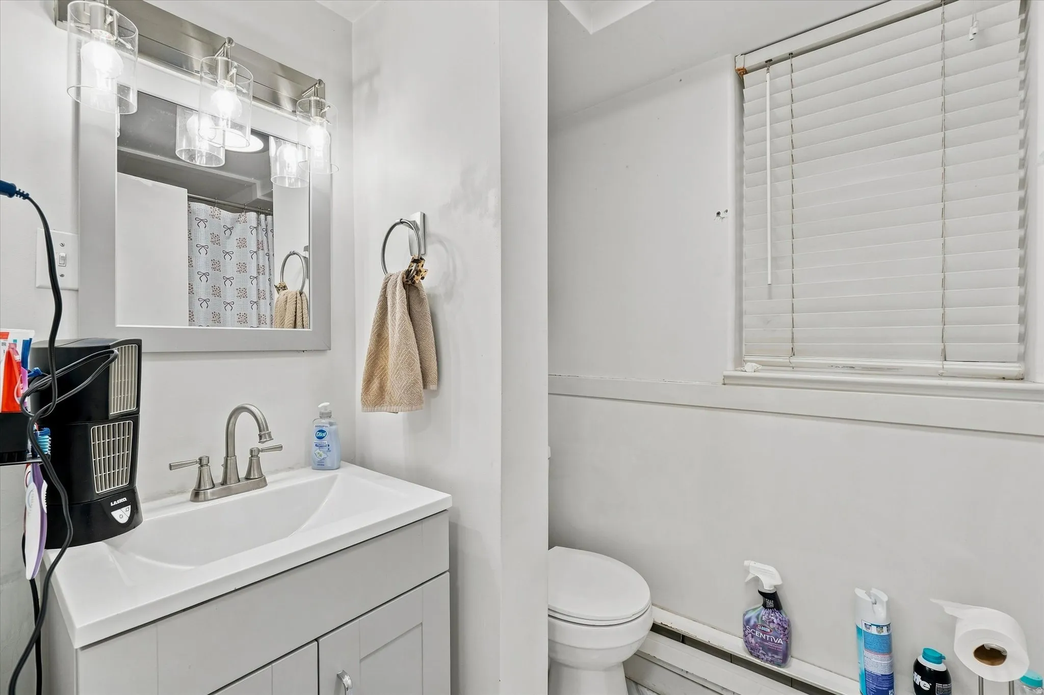 Vanity with integrated sink, brushed nickel faucet, wall-mounted mirror, and overhead lighting fixture