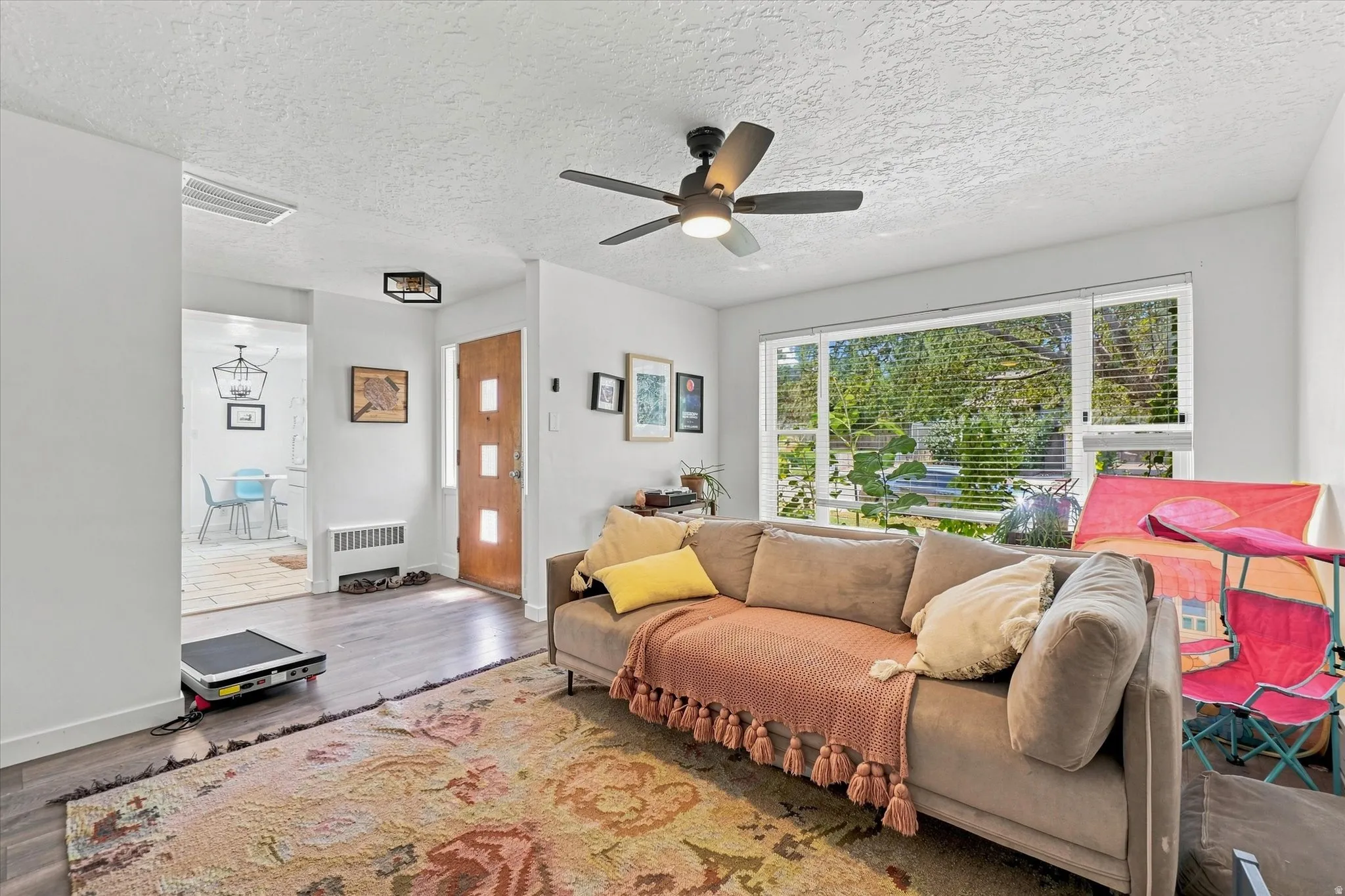 Spacious living area featuring a ceiling fan, large picture window, and wood-finish flooring