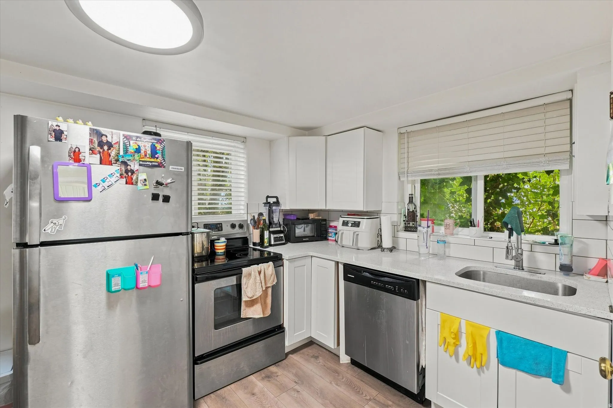 Stainless steel refrigerator, range, and dishwasher complement white cabinetry and countertops