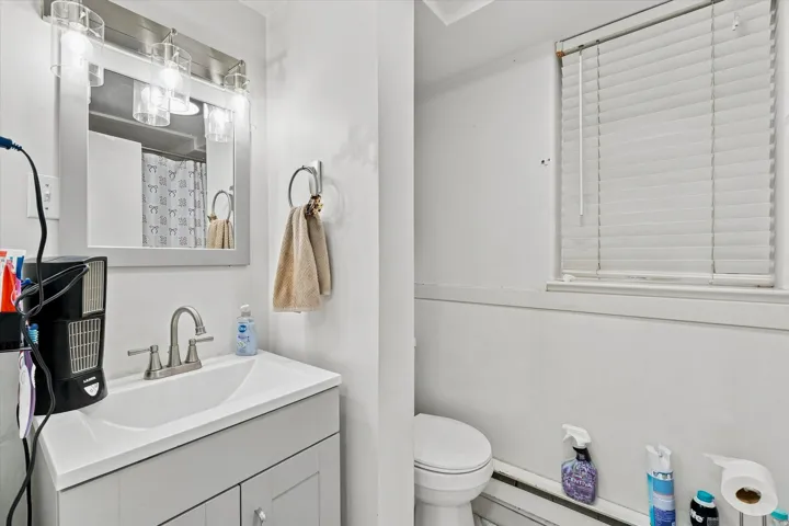 Vanity with integrated sink, brushed nickel faucet, wall-mounted mirror, and overhead lighting fixture