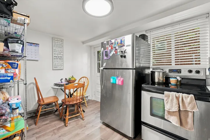 Stainless steel appliances, wood-finish flooring, white walls, and a round overhead light fixture