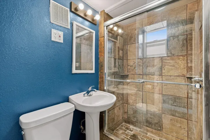 Pedestal sink, tile shower surround, glass shower enclosure, and fixed window