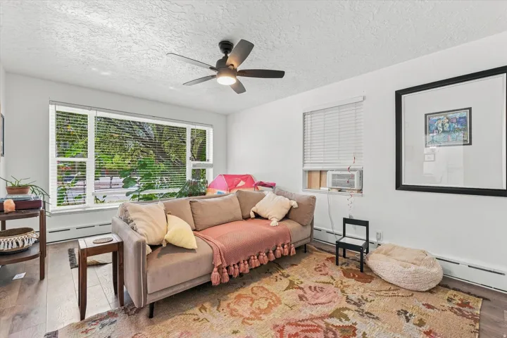 Hardwood-finish flooring, a ceiling fan with integrated lighting, and multiple windows providing natural light