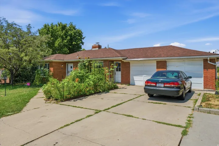 Red brick exterior featuring a brown shingle roof, attached two-car garage, and a concrete driveway