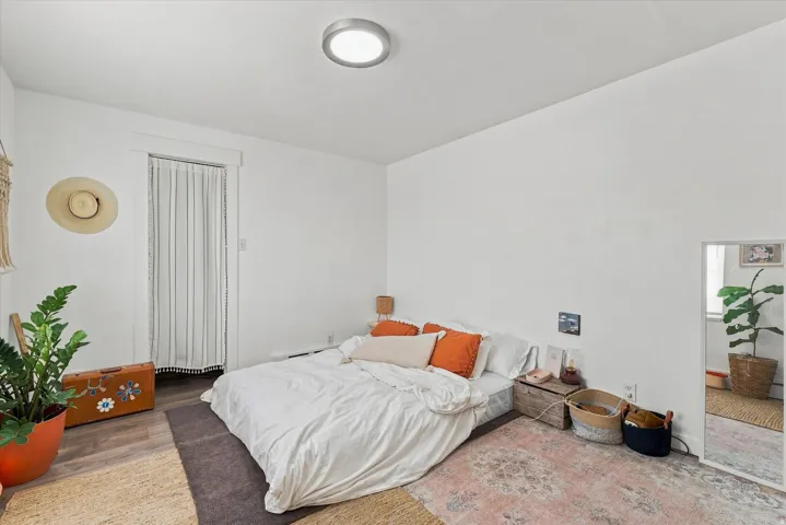 Neutral white wall finishes, wood-finish flooring, and a flush-mount ceiling light fixture