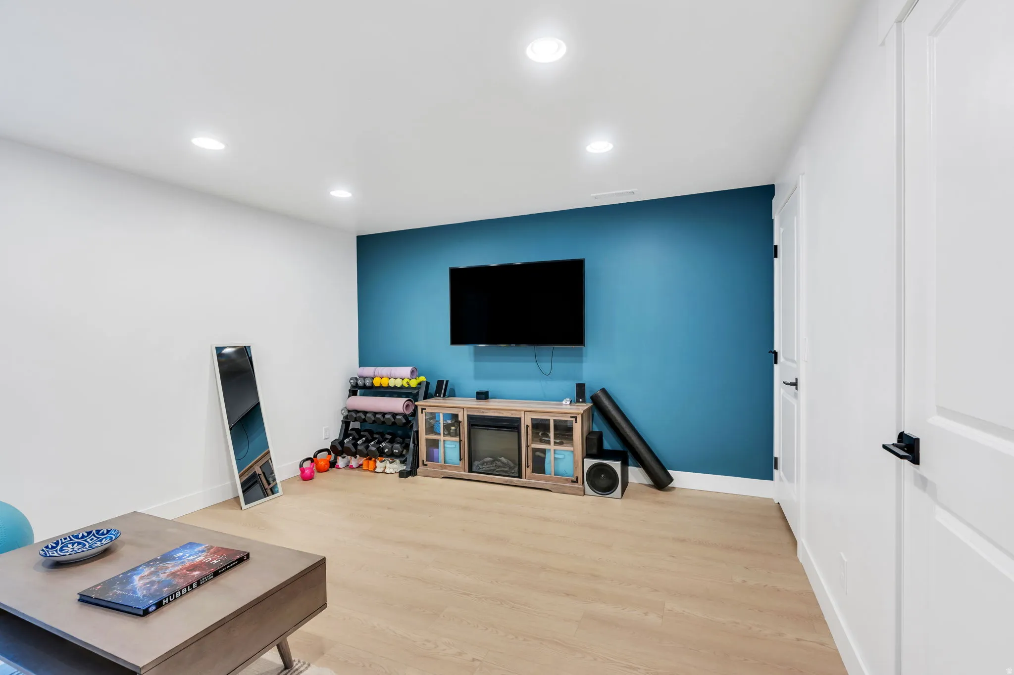 Spacious room featuring light wood-finish flooring, recessed lighting, and a vibrant accent wall