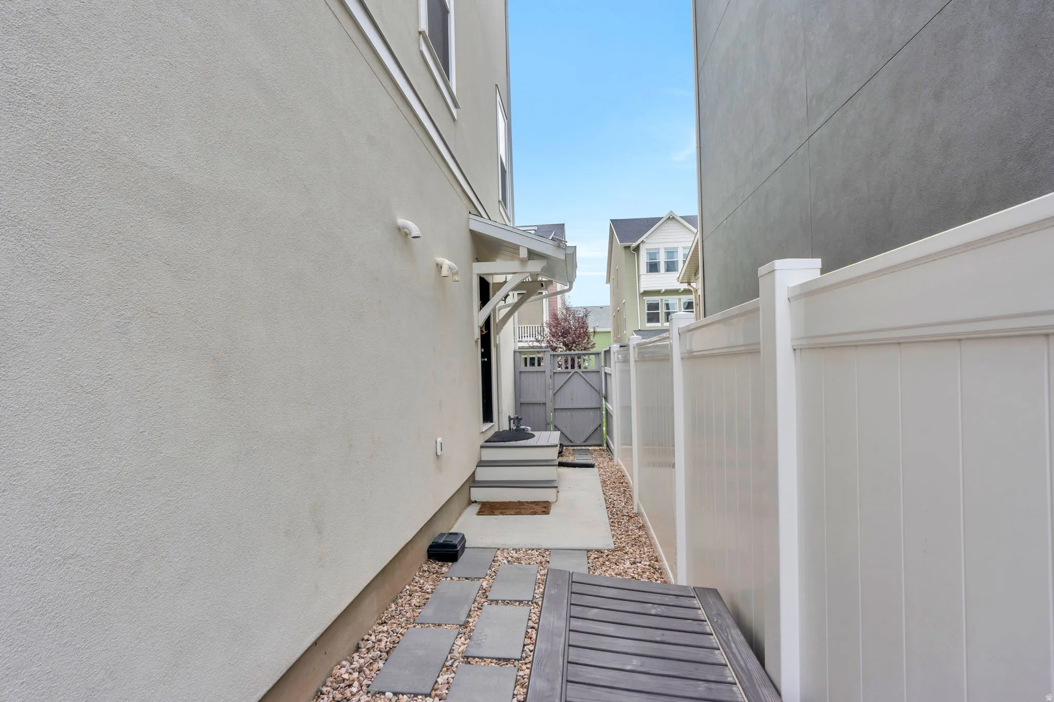 Side yard featuring a white privacy fence and a stone path with stepping stones