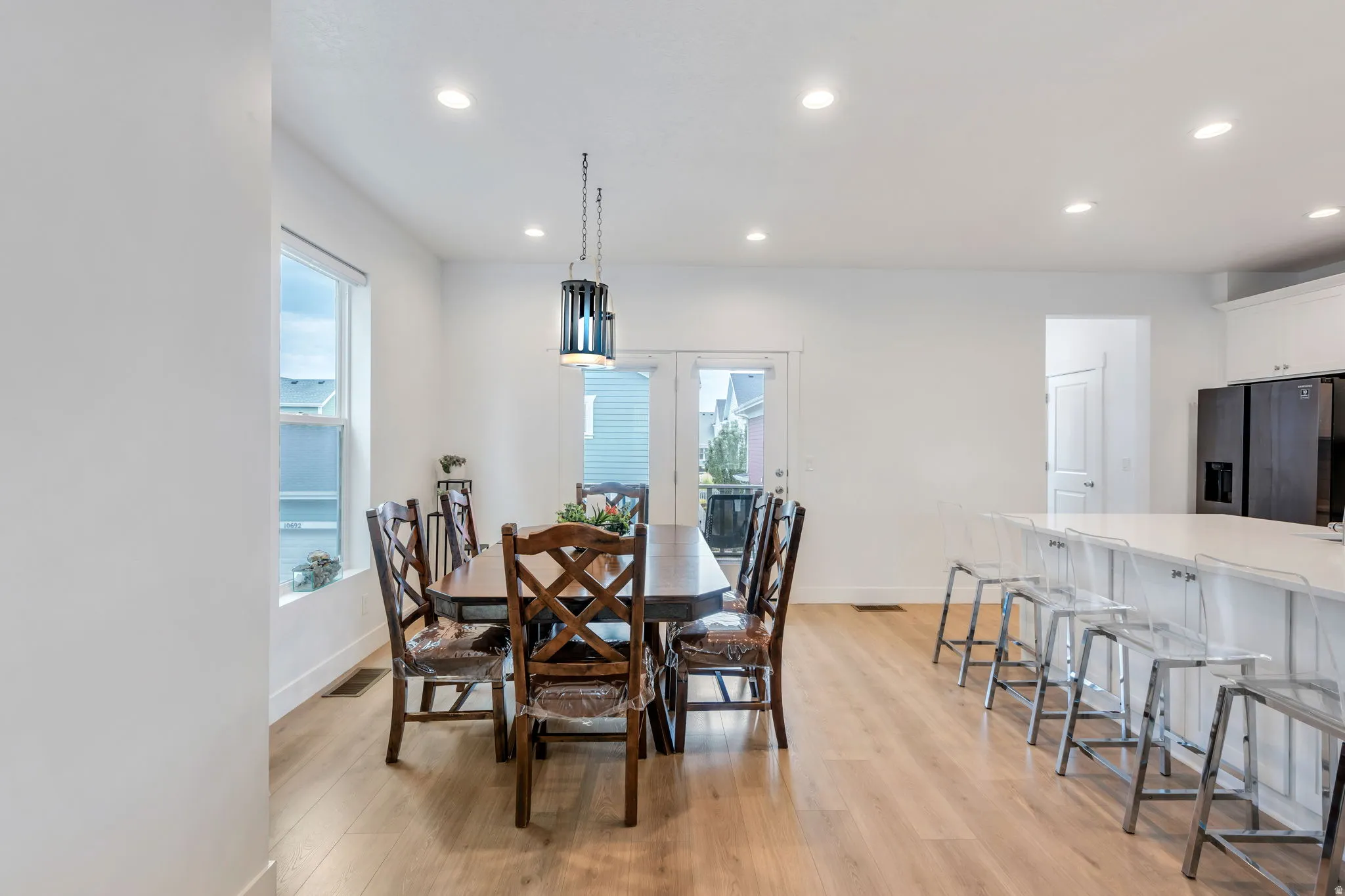 Open-concept dining area featuring wood-finish flooring, recessed lighting, and a modern pendant light fixture