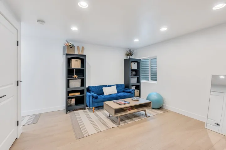 Spacious room featuring light wood-finish flooring, recessed ceiling lighting, and a white color palette