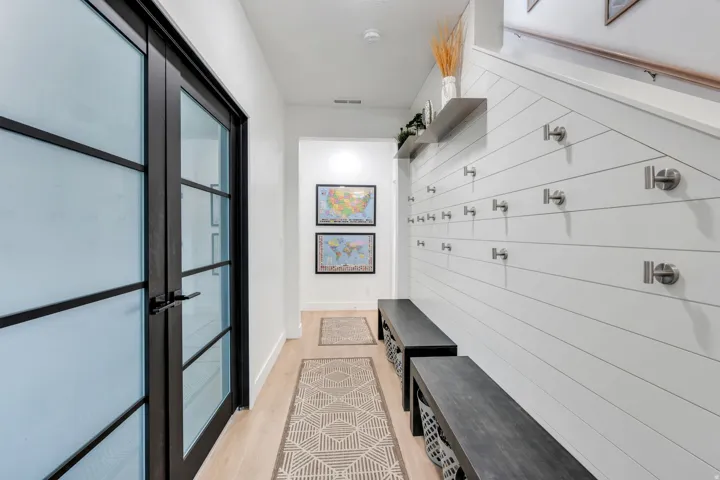 Entryway featuring light wood-finish flooring, white shiplap wall paneling, and a built-in bench system with integrated hooks