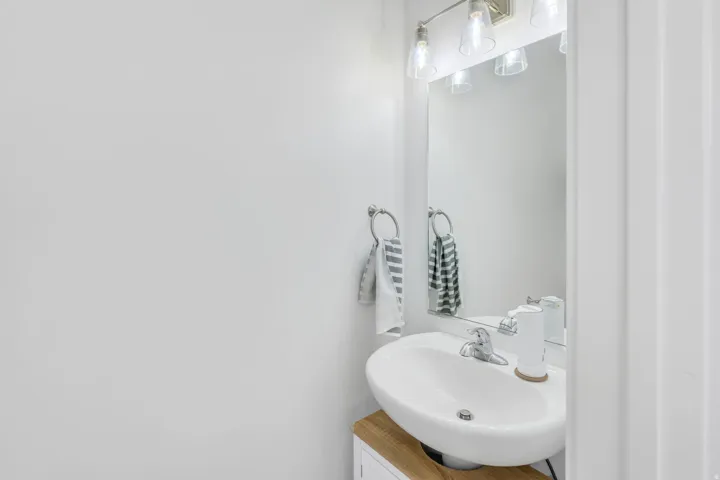 Bathroom vanity featuring a white oval sink, chrome faucet, and a wood-finish countertop