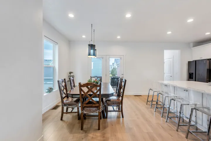 Open-concept dining area featuring wood-finish flooring, recessed lighting, and a modern pendant light fixture
