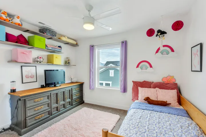 Room featuring white walls, carpet flooring, a window with purple drapes, and a ceiling fan