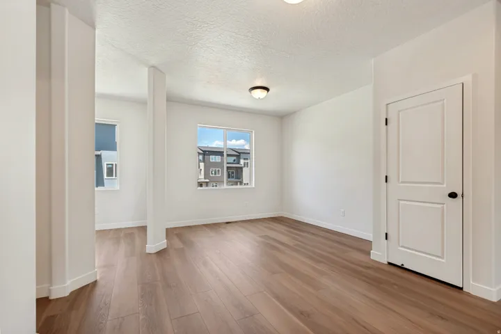Spacious interior room featuring wood-finish flooring, bright white walls, and a recessed ceiling light fixture