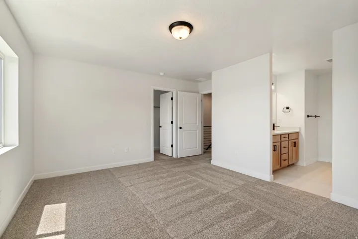 Spacious room featuring neutral carpeting, white walls, a recessed window, and a built-in vanity with a sink