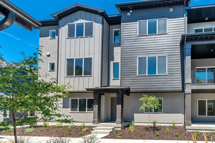 Contemporary multi-level townhome featuring a mixed-material facade with vertical siding, horizontal siding, and stucco finishes