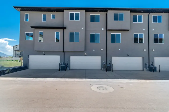 Modern multi-level townhome featuring a neutral gray stucco exterior