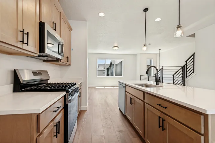 Modern kitchen featuring light wood-finish cabinetry, stainless steel appliances, and white countertops