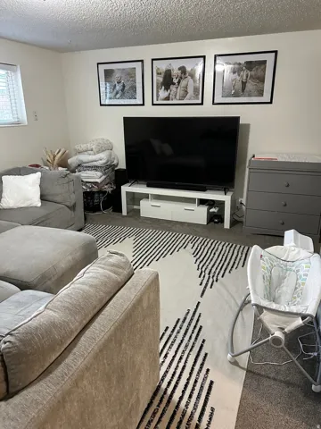 Spacious living area featuring light-colored walls and a textured ceiling