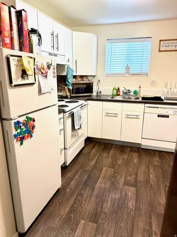 Kitchen featuring white cabinetry with brushed nickel hardware, dark wood-finish flooring, and a white appliance suite