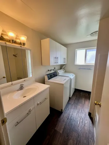 Bathroom featuring a white vanity with integrated sink, dark wood-finish flooring, and a mirrored medicine cabinet