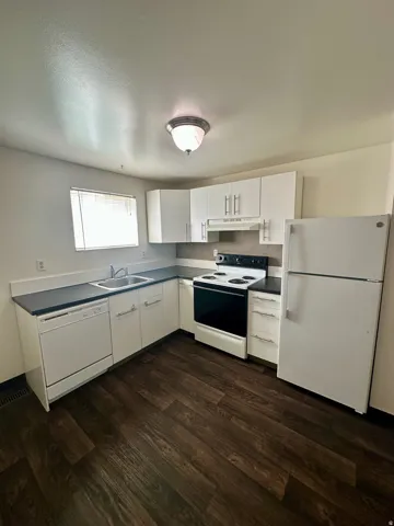 Kitchen featuring white cabinetry, dark wood-finish flooring, and white appliances