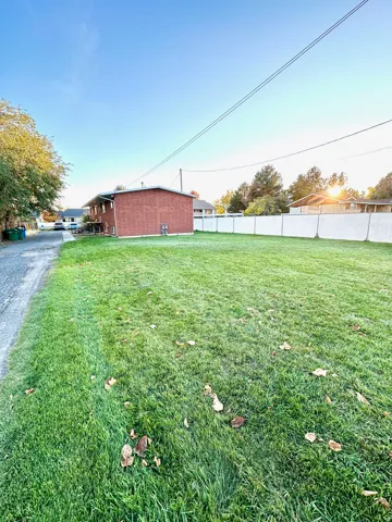 Expansive green lawn with a white chain-link fence defining the property boundary