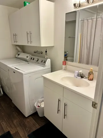 Dedicated laundry area featuring upper cabinetry and wood-finish flooring